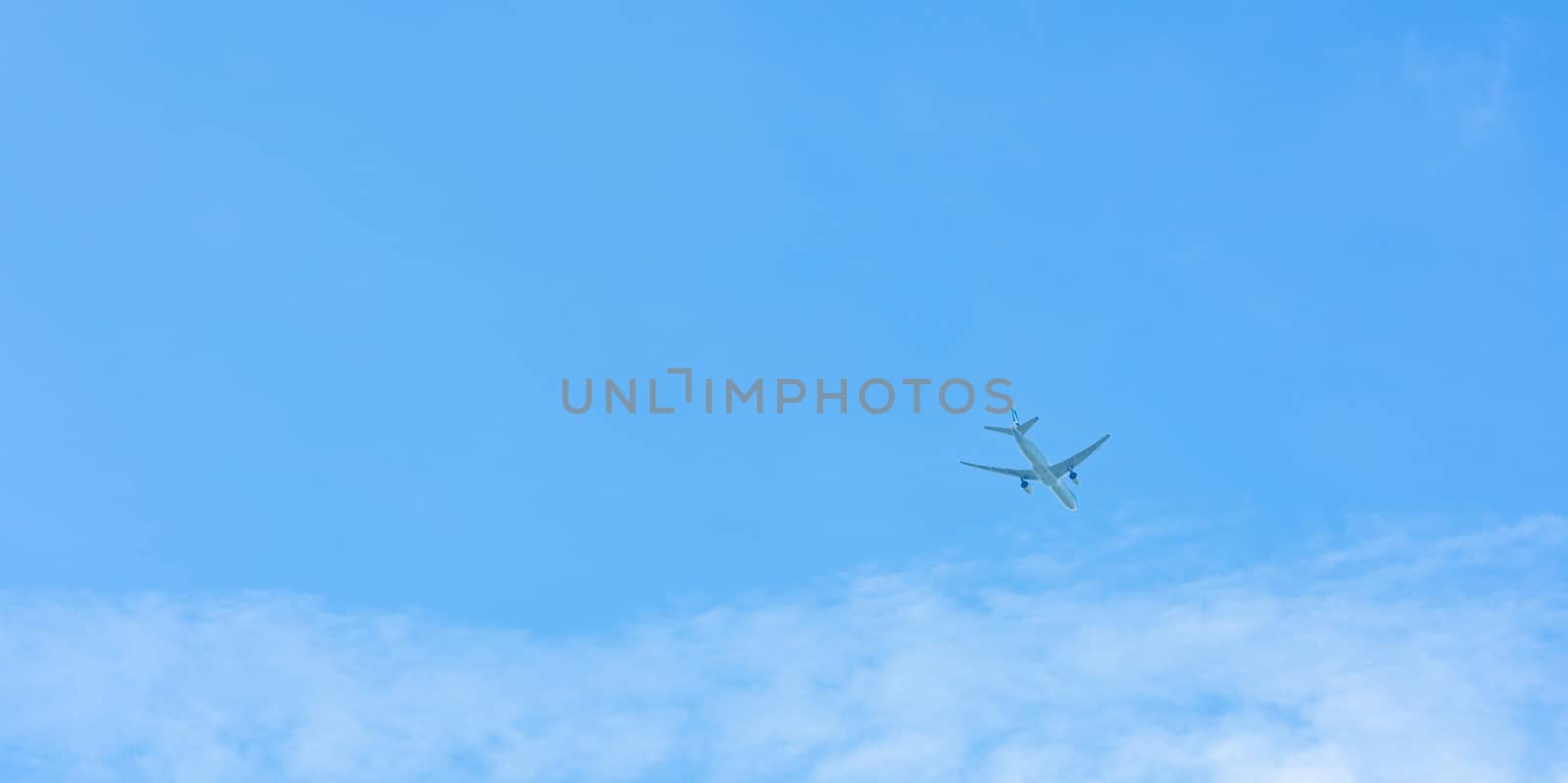Airplane on blue sky and white clouds. Commercial airline flying on blue sky. Travel flight for vacation. Aviation transport. by Fahroni