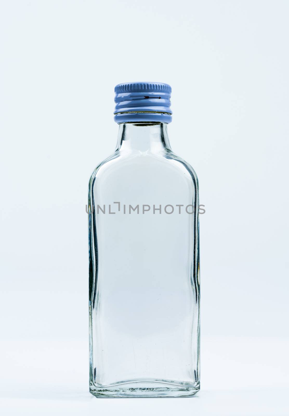 Empty transparent glass bottle with closed aluminum cap isolated on white background with blank label and copy space. Use for beverage or medicine product design template. Glass bottle packaging.