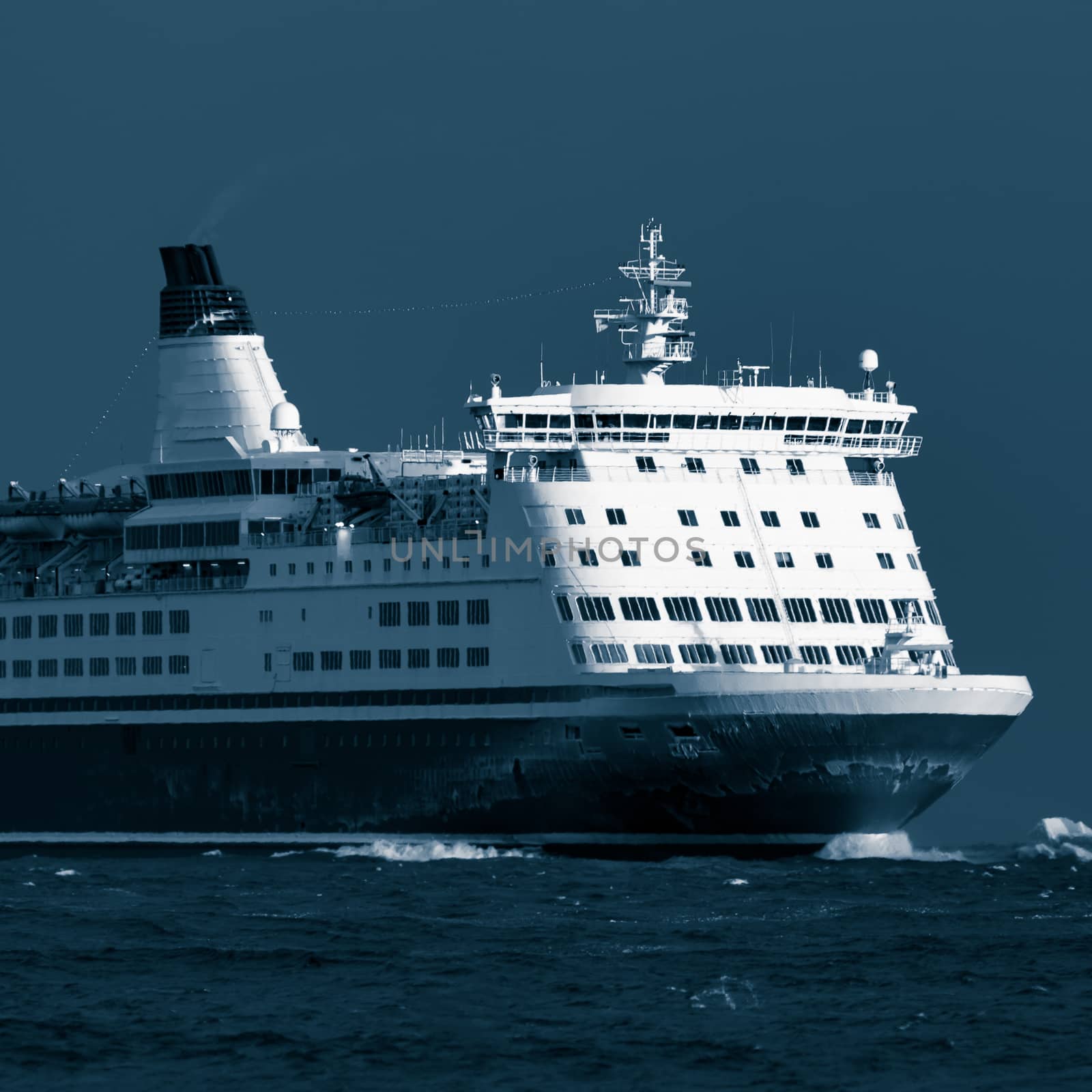 Passenger ship sailing from the sea in the morning. Toned dark blue