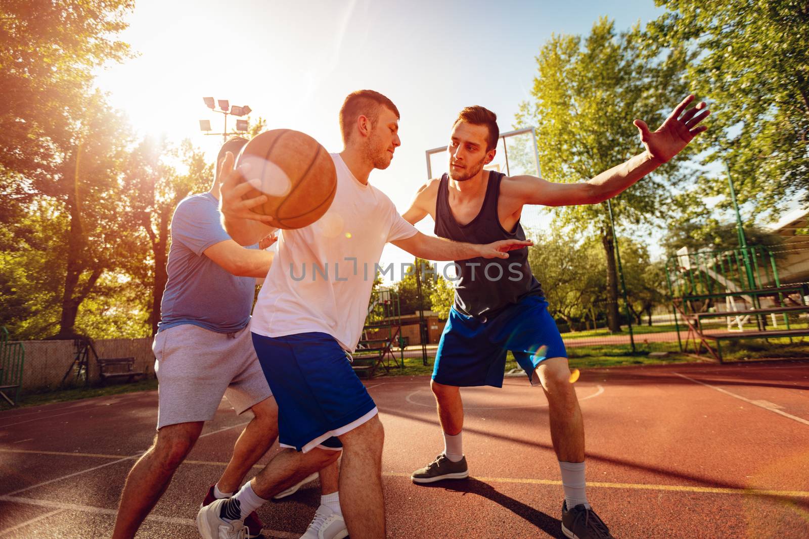 Young basketball players have a training outdoor. They are playing and making action together.