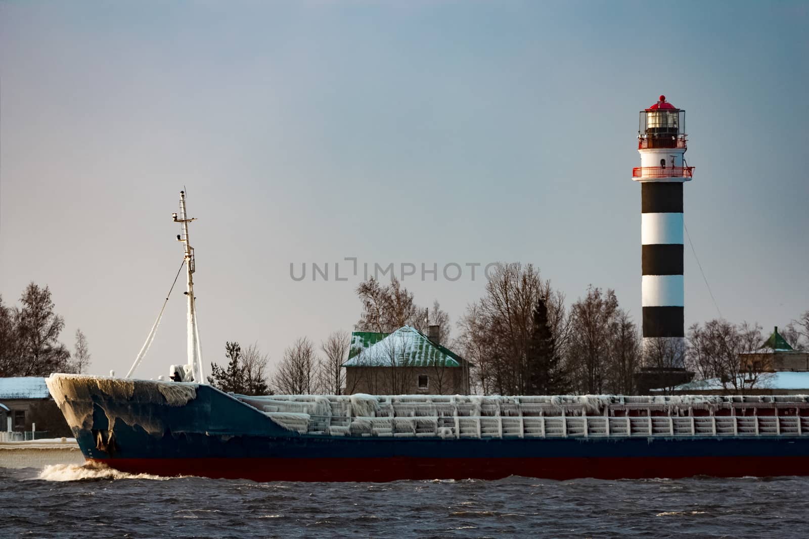 Blue bulk carrier moving from the sea in cold winter