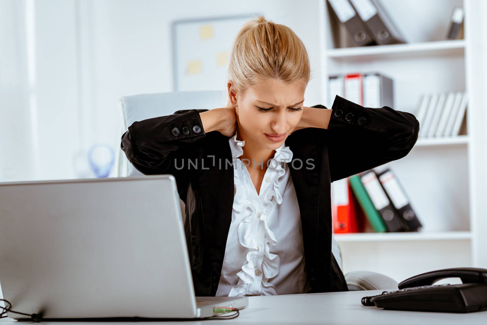 Young stressed business woman holding hands on the neck with a pained expression on her face.
