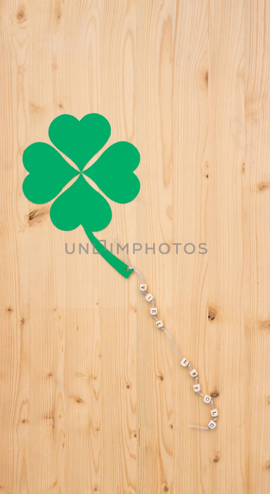 The german words for lot of success and a cloverleaf on a cord on wood
