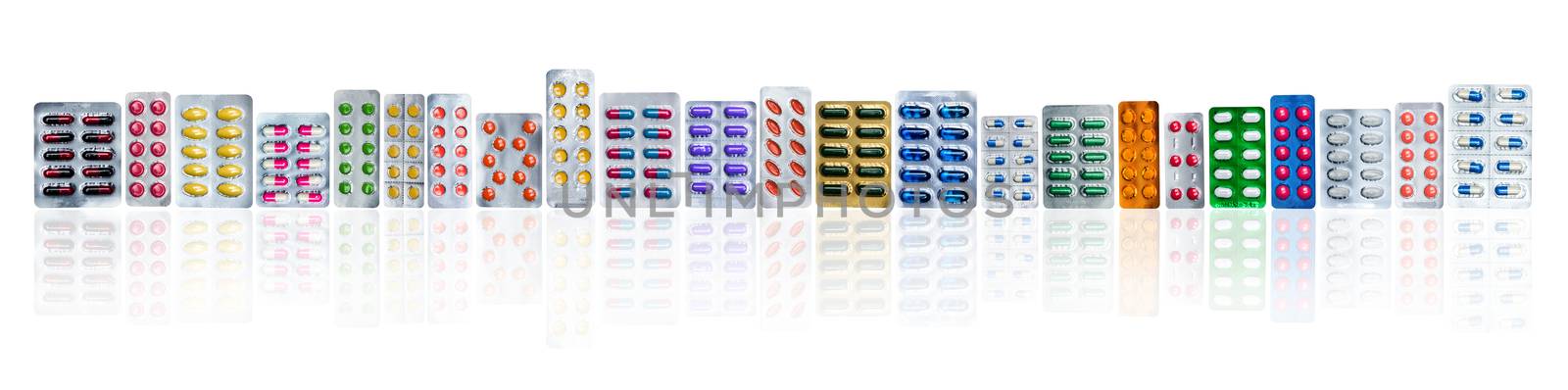 Many of colorful pills in blister packs in a row isolated on white background with copy space. Pharmaceuticals industry. Healthcare education in hospital. Pharmacology. Painkiller and antibiotics