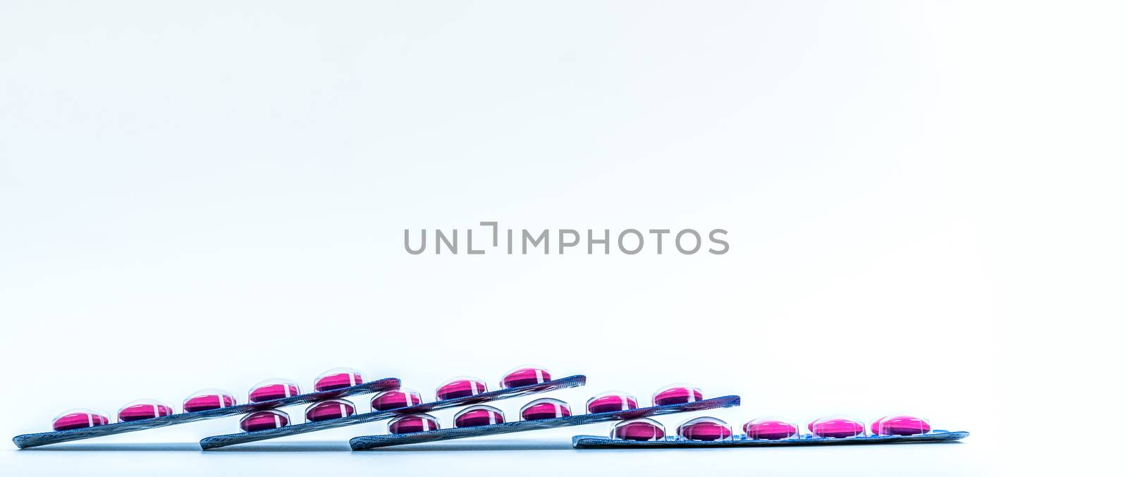 Side view of pink tablets pill in blister pack isolated on white background with copy space. Ibuprofen for relief pain, headache, high fever and anti-inflammatory. Painkiller pills. Healthcare concept by Fahroni