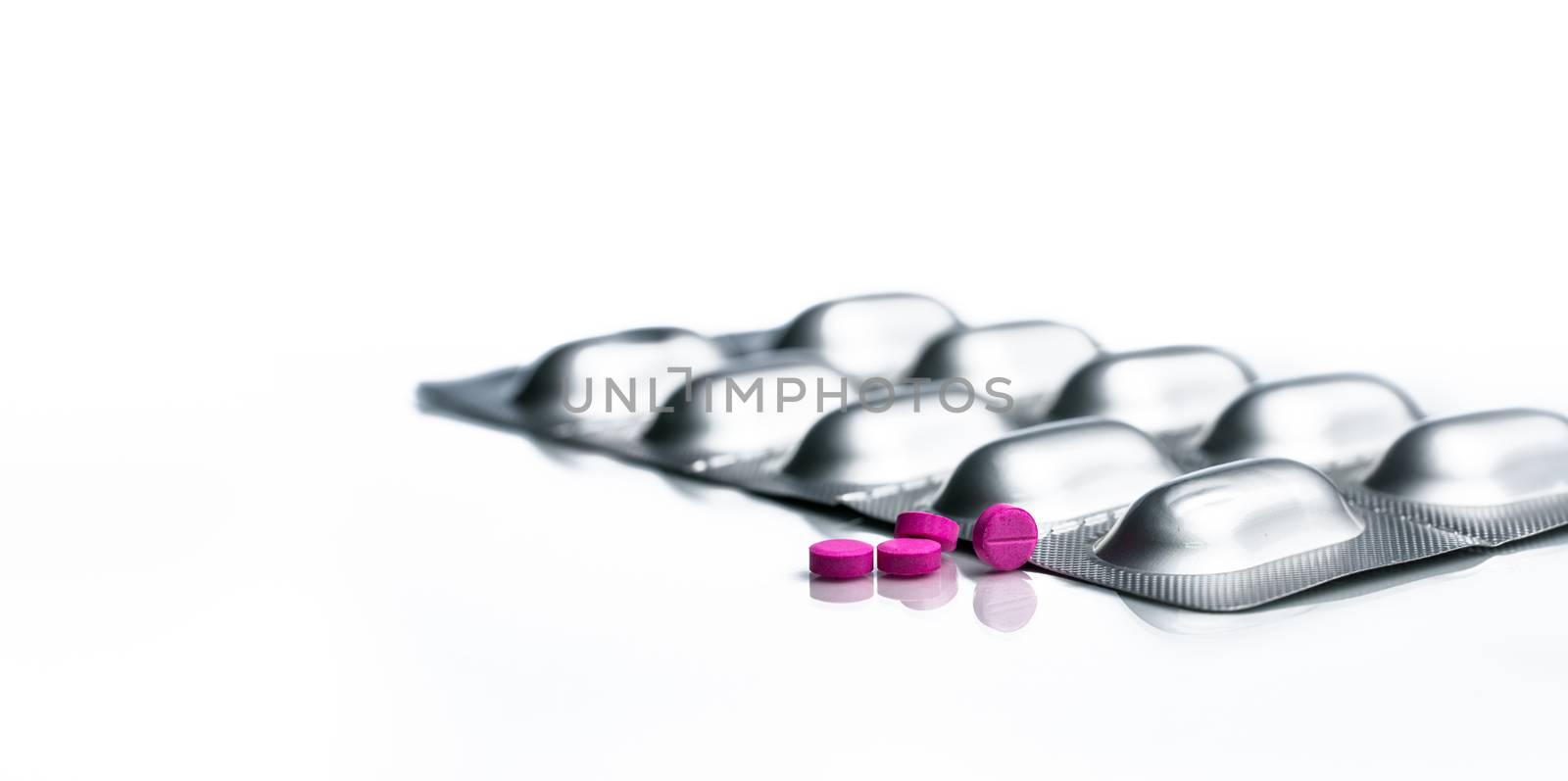 Small pink tablets pills and aluminium foil blister pack of pills isolated on white background with copy space. by Fahroni