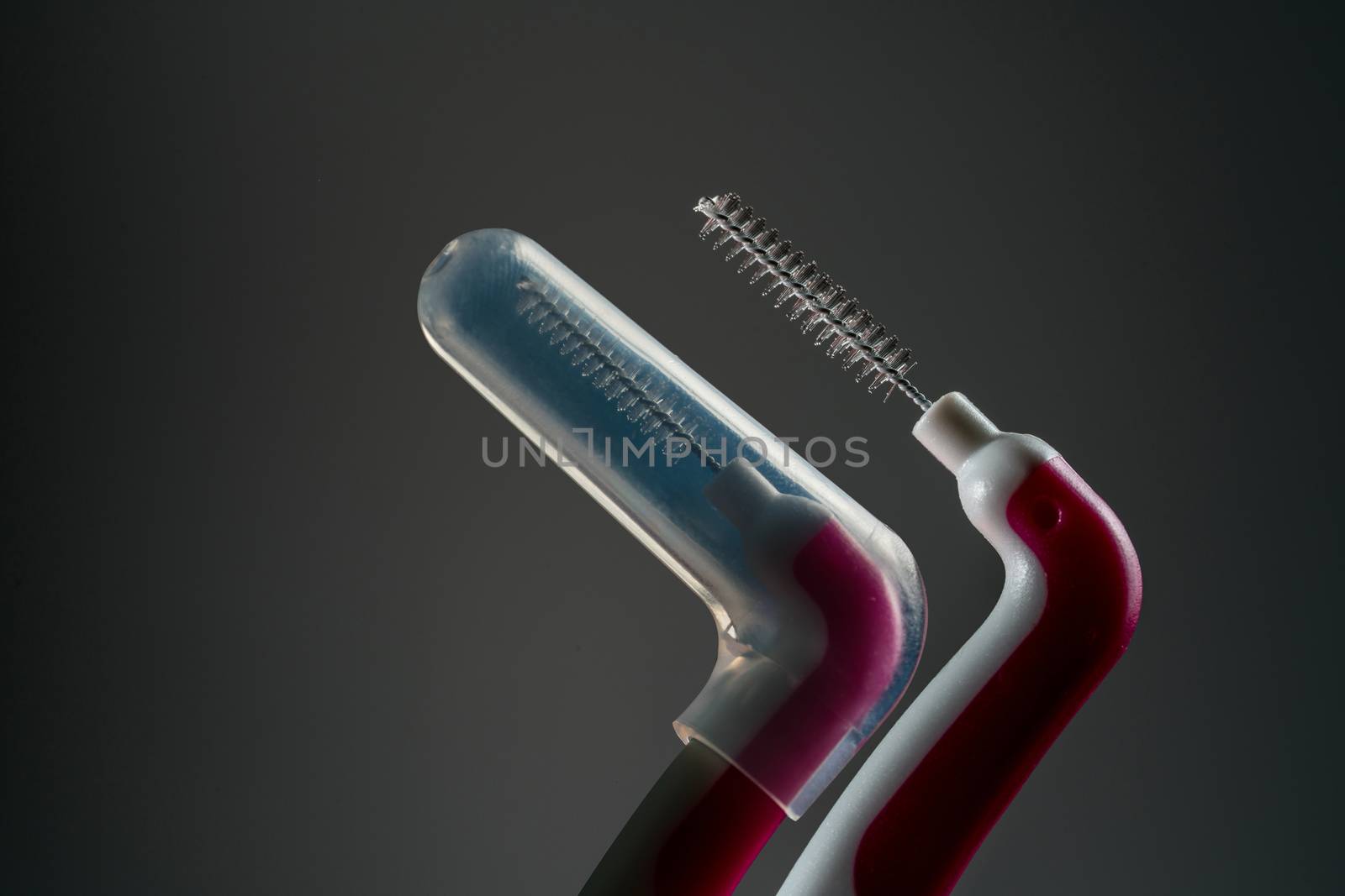 Interdental brush with opened cover isolated on dark background with copy space. Dental care concept. Equipment for get rid of food stuck in teeth