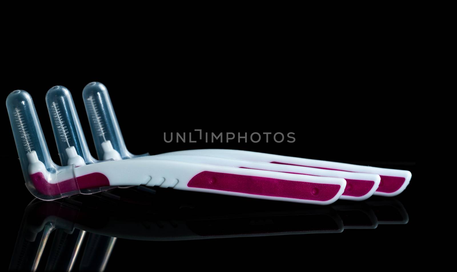 Three interdental brush with cover isolated on dark background with copy space. Dental care concept. Equipment for get rid of food stuck in teeth by Fahroni