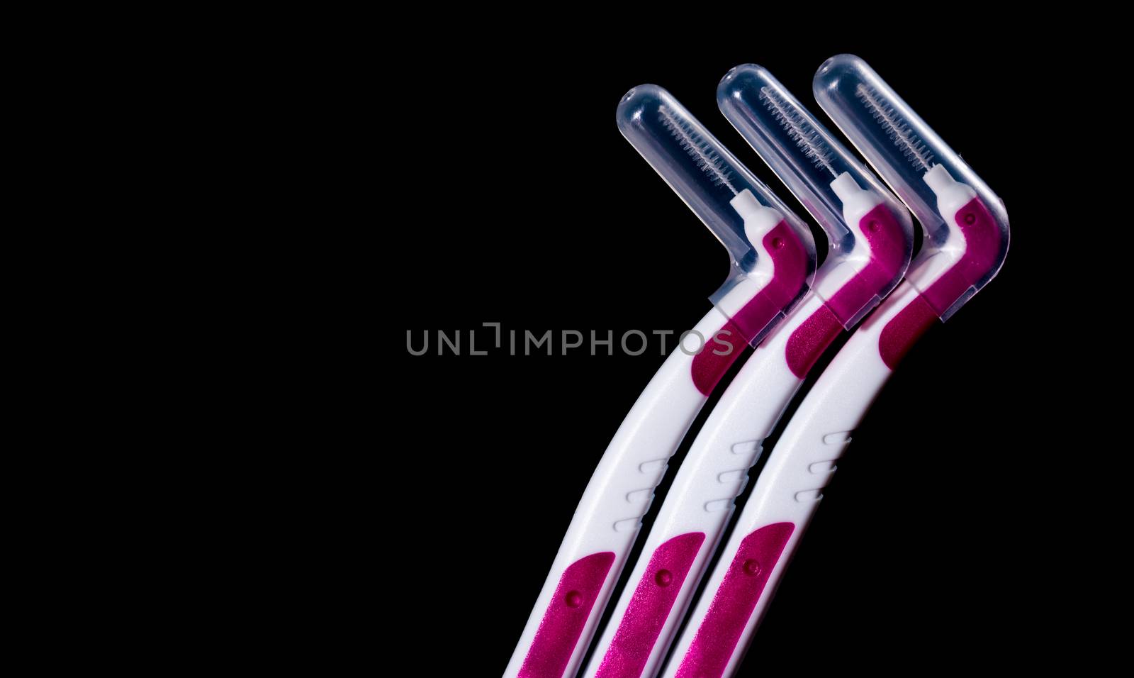 Three interdental brush with cover isolated on black background with copy space for text. Dental care concept. Equipment for get rid of food stuck in teeth