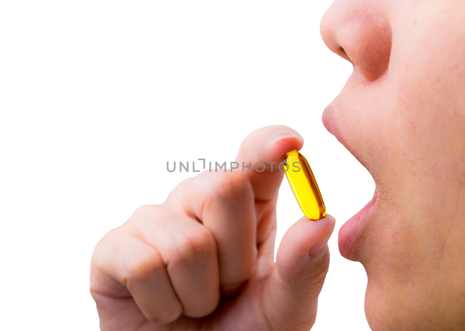 Young woman hand hold fish oil capsule near open mouth. Woman taking omega-3 pills. Vitamins and supplements concept.