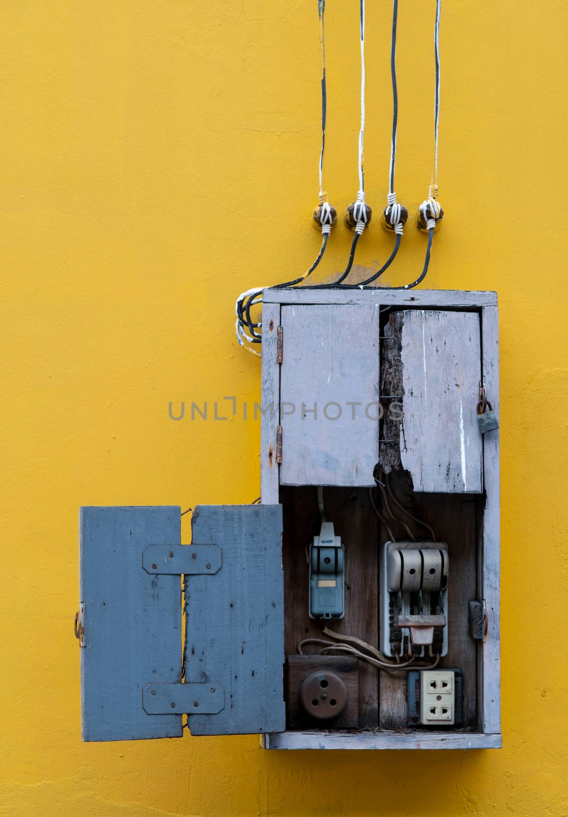 Wooden box, electric control equipment in the factory on yellow vintage concrete wall background. Manual cut out with old design. Safety in home and factory industrial concept.