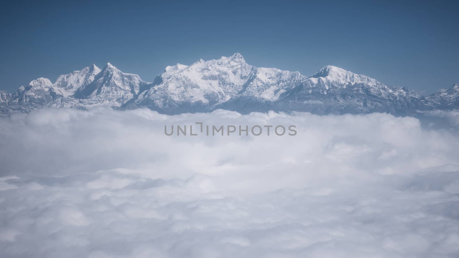 The Himalayas as seen from an airplane in Nepal. Layer of clouds beneath the mountain tops.