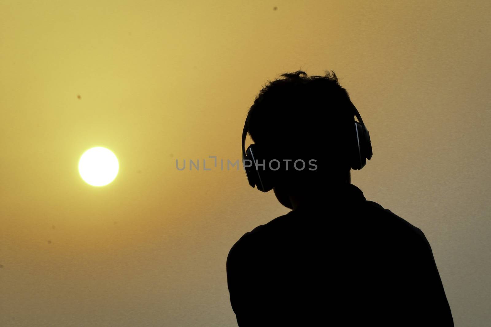 Silhouette of man with headphones on sunset sky background by sudiptabhowmick
