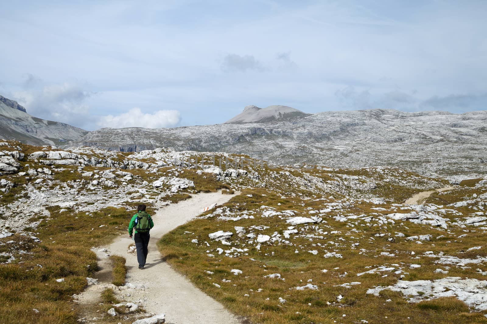 Hiker walking on a path in Dolomites, Italy