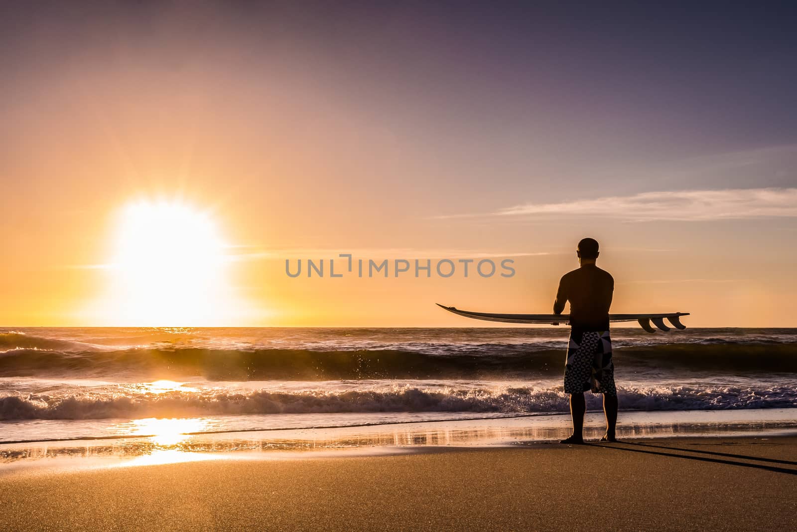 Surfer watching the waves at sunset in Portugal.