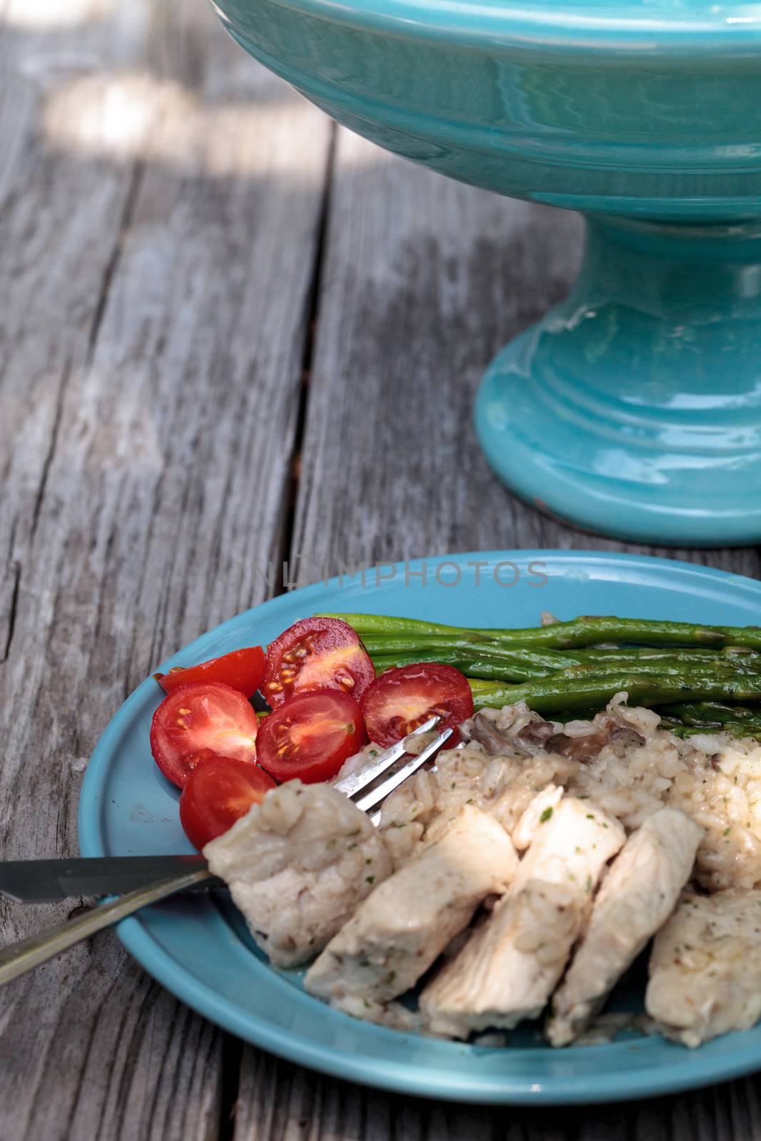 Sauteed pork and asparagus with mushroom risotto meal on a rustic dinner plate