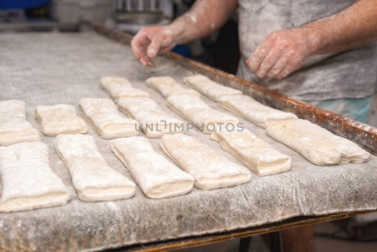 Baker preparing uncooked bread dough loaves ready to bake by HERRAEZ