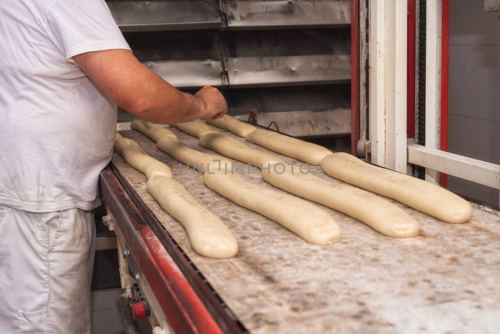 Baker preparing uncooked bread dough loaves ready to bake by HERRAEZ