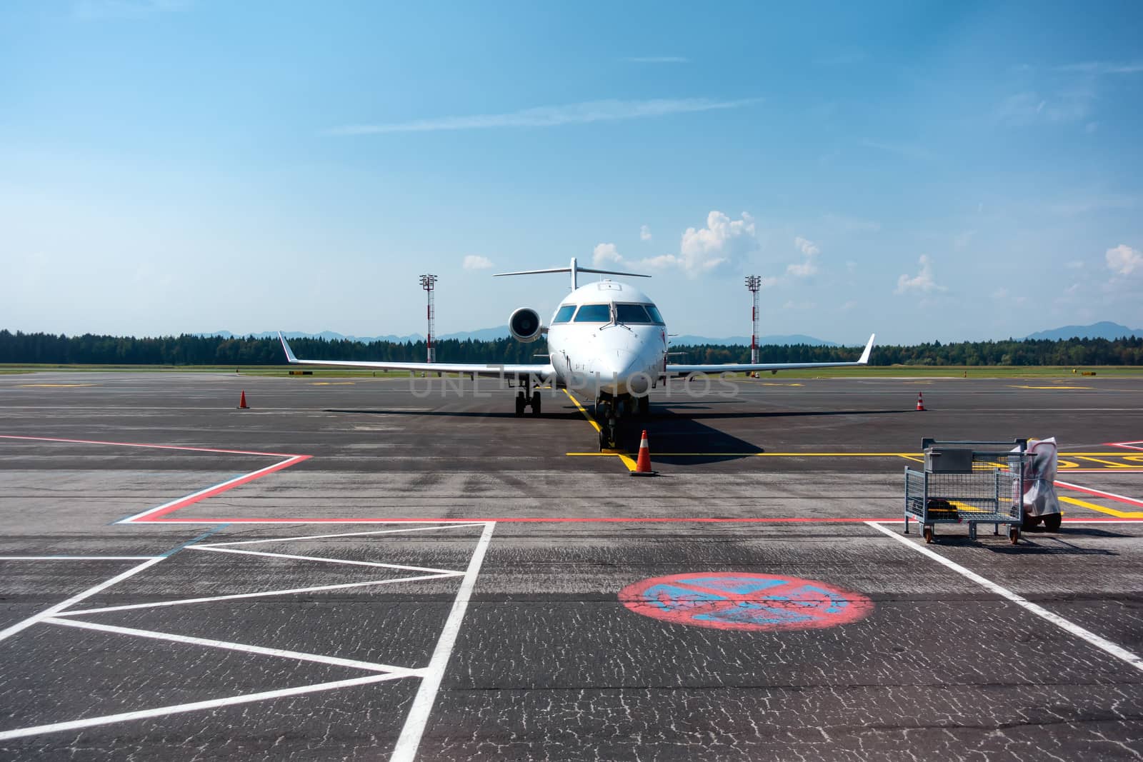 Small business, commuter jet airplane on airport, head on with apron markings on ground, copyspace