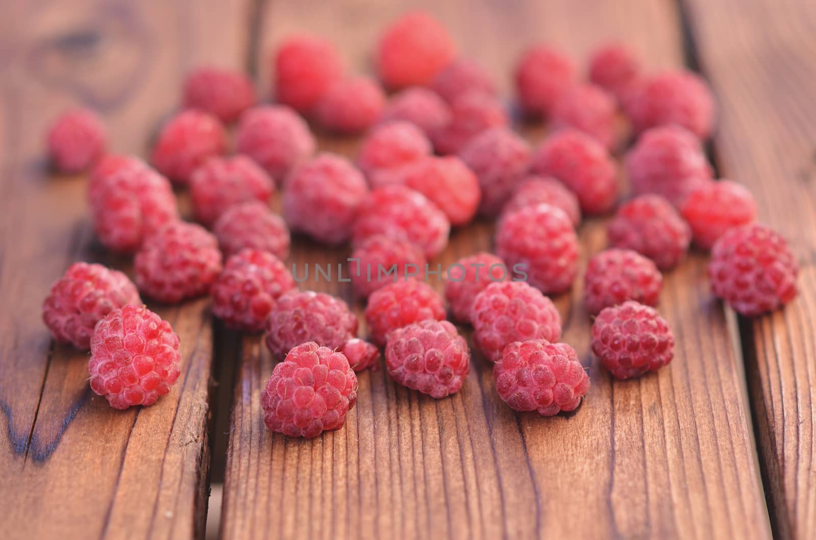 On a wooden background, raspberries spread across the plane, photos on the side