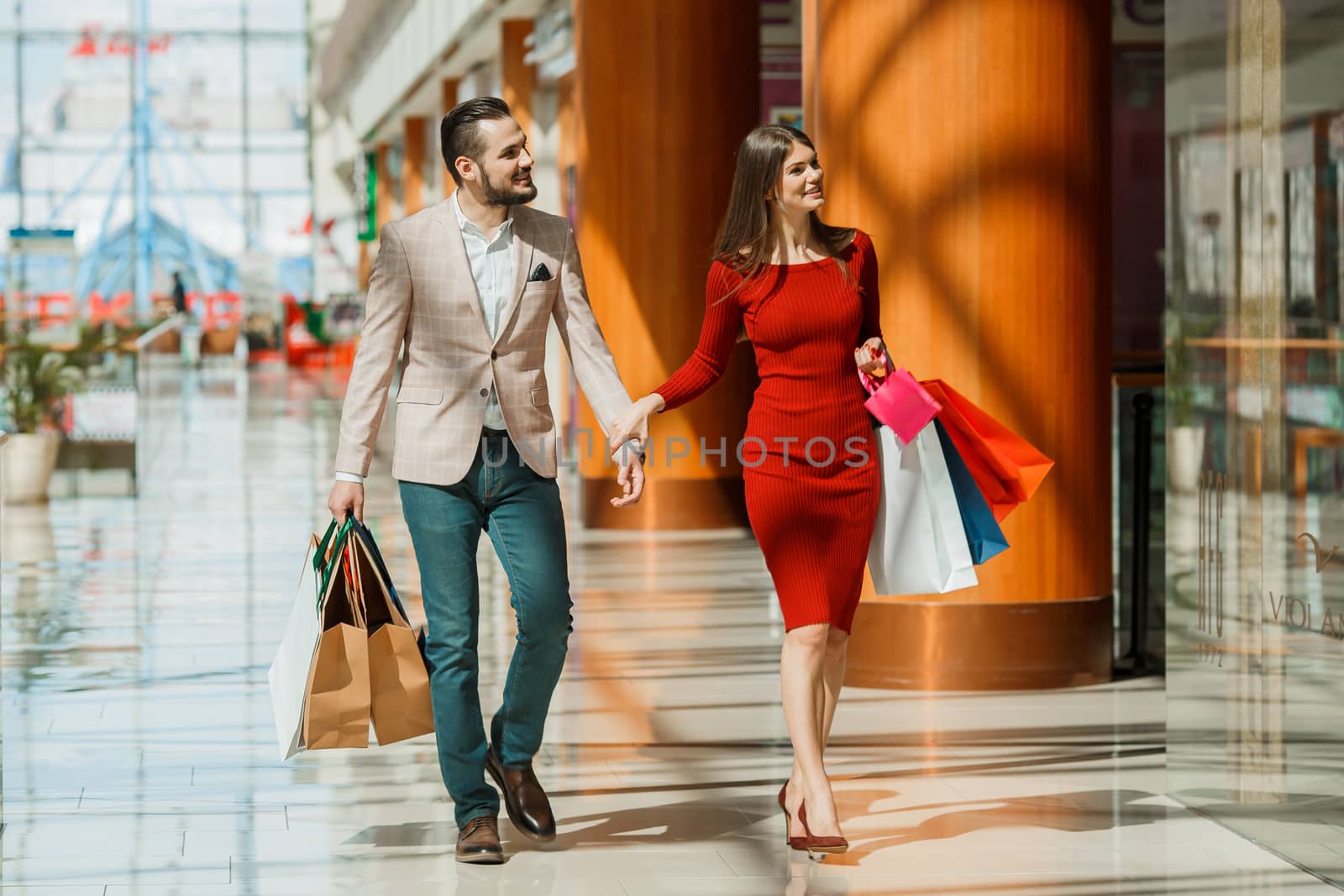 Happy beautiful young couple with shopping bags in mall