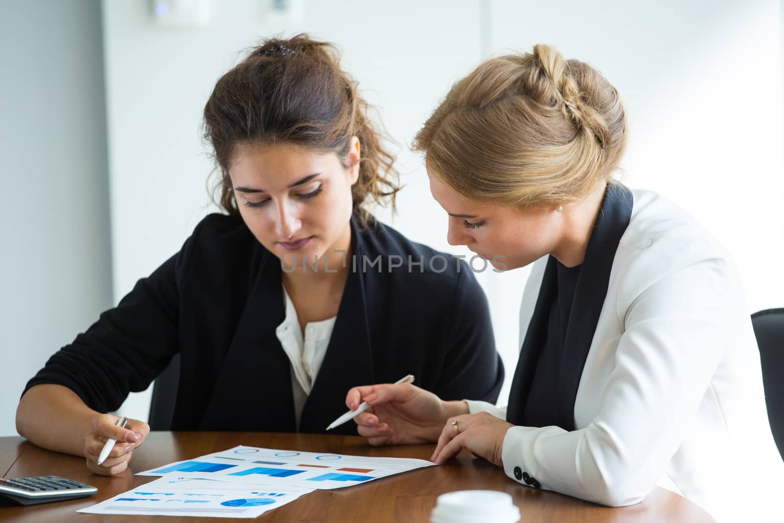 Business women working with financial diagrams, discussing financial reports at workplace