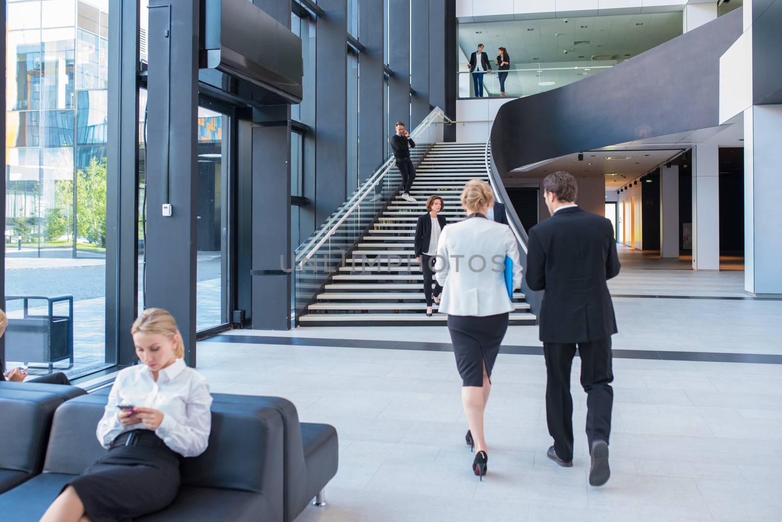 Modern business people walking in glass hall of office building
