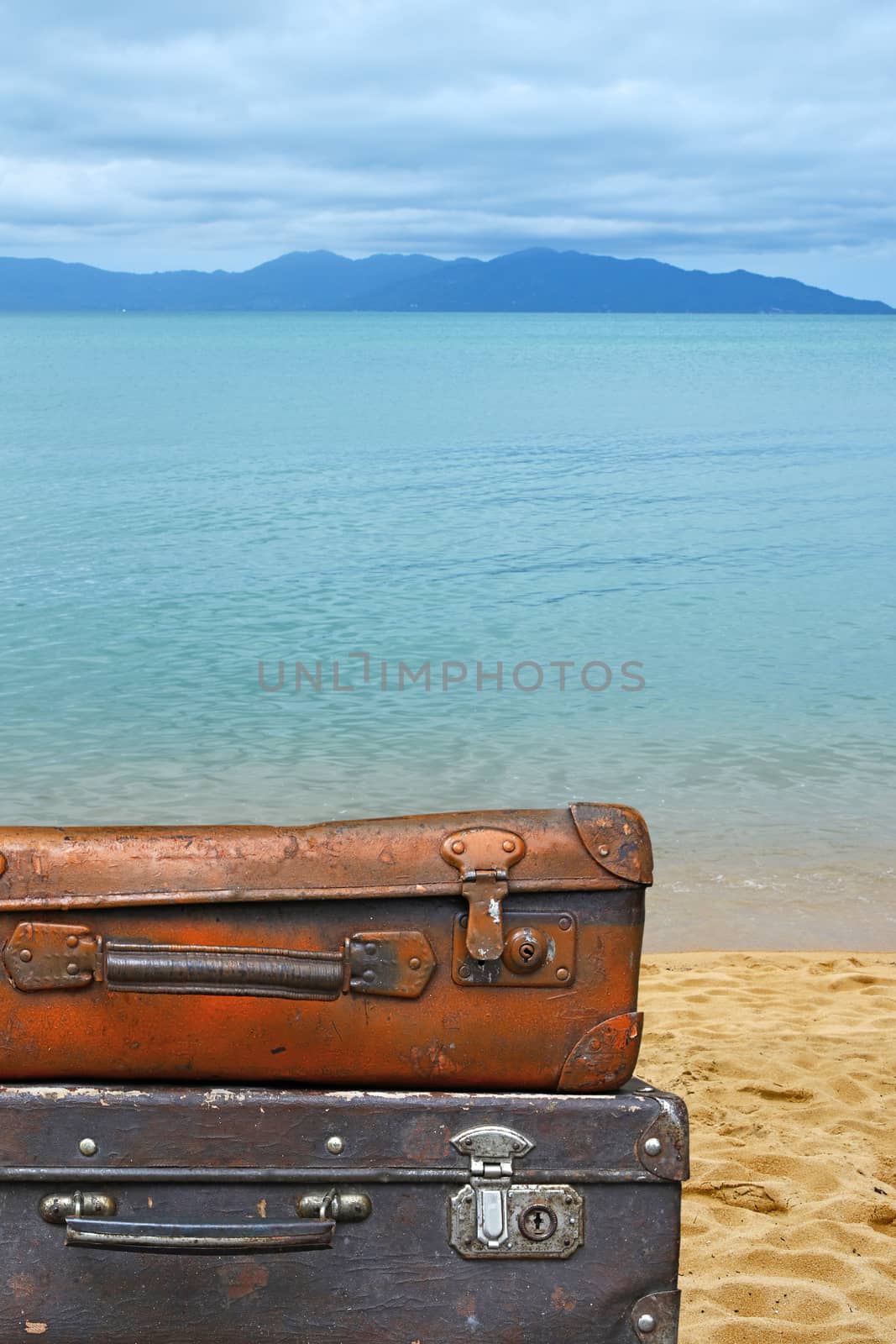 Close up stack of two old vintage antique grunge travel luggage brown leather suitcase trunks isolated over background of sea beach, low angle side view