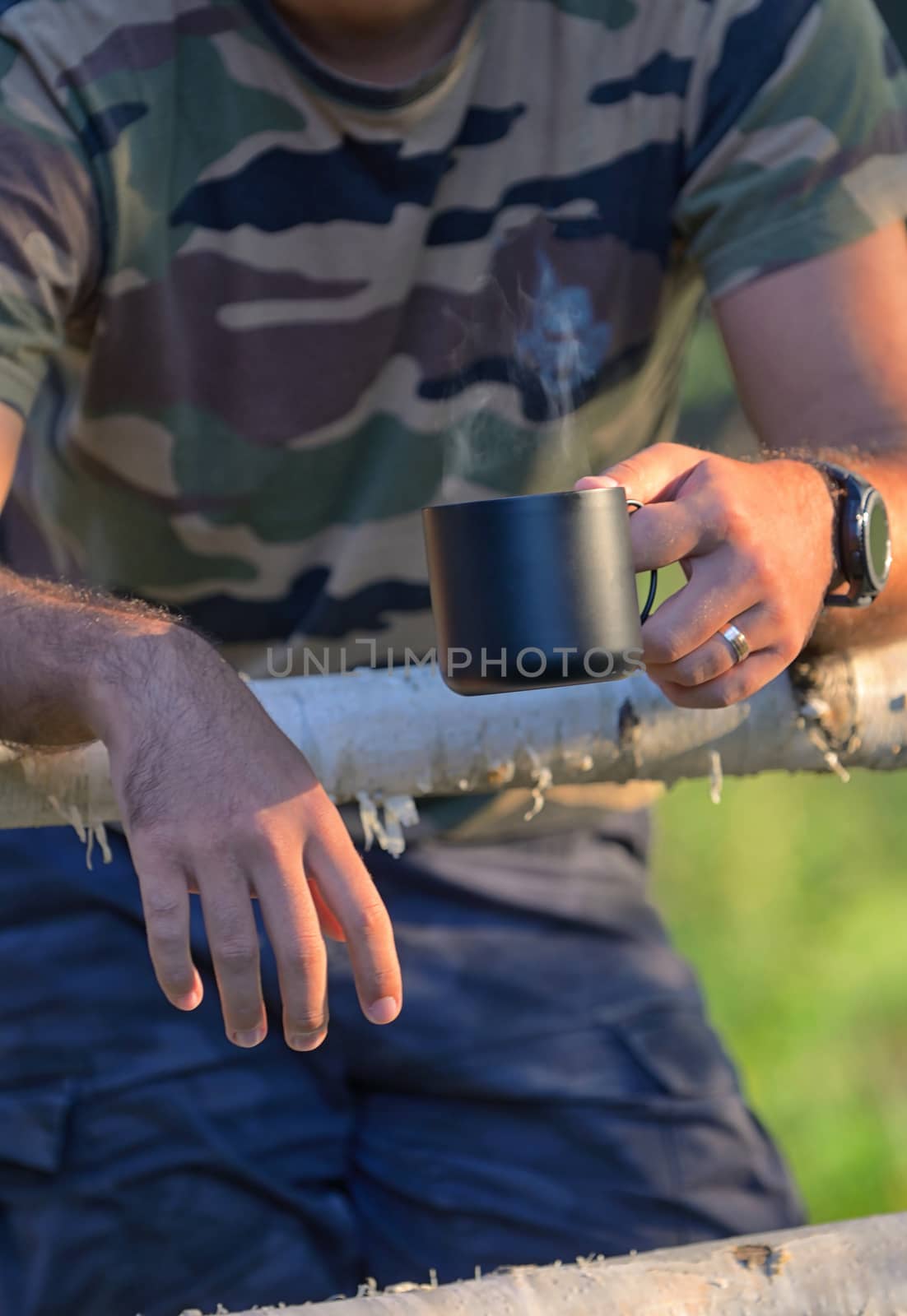 Man drinking coffee on fenced ranch in morning 