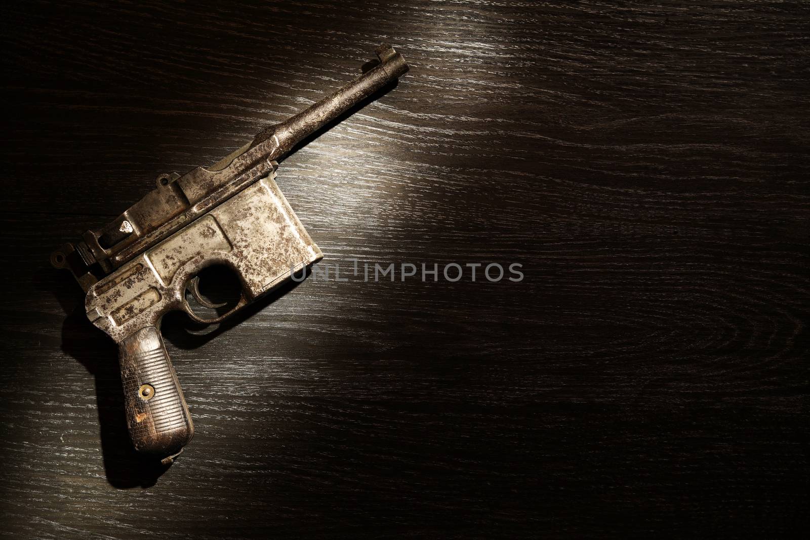 Old military pistol on dark background under beam of light