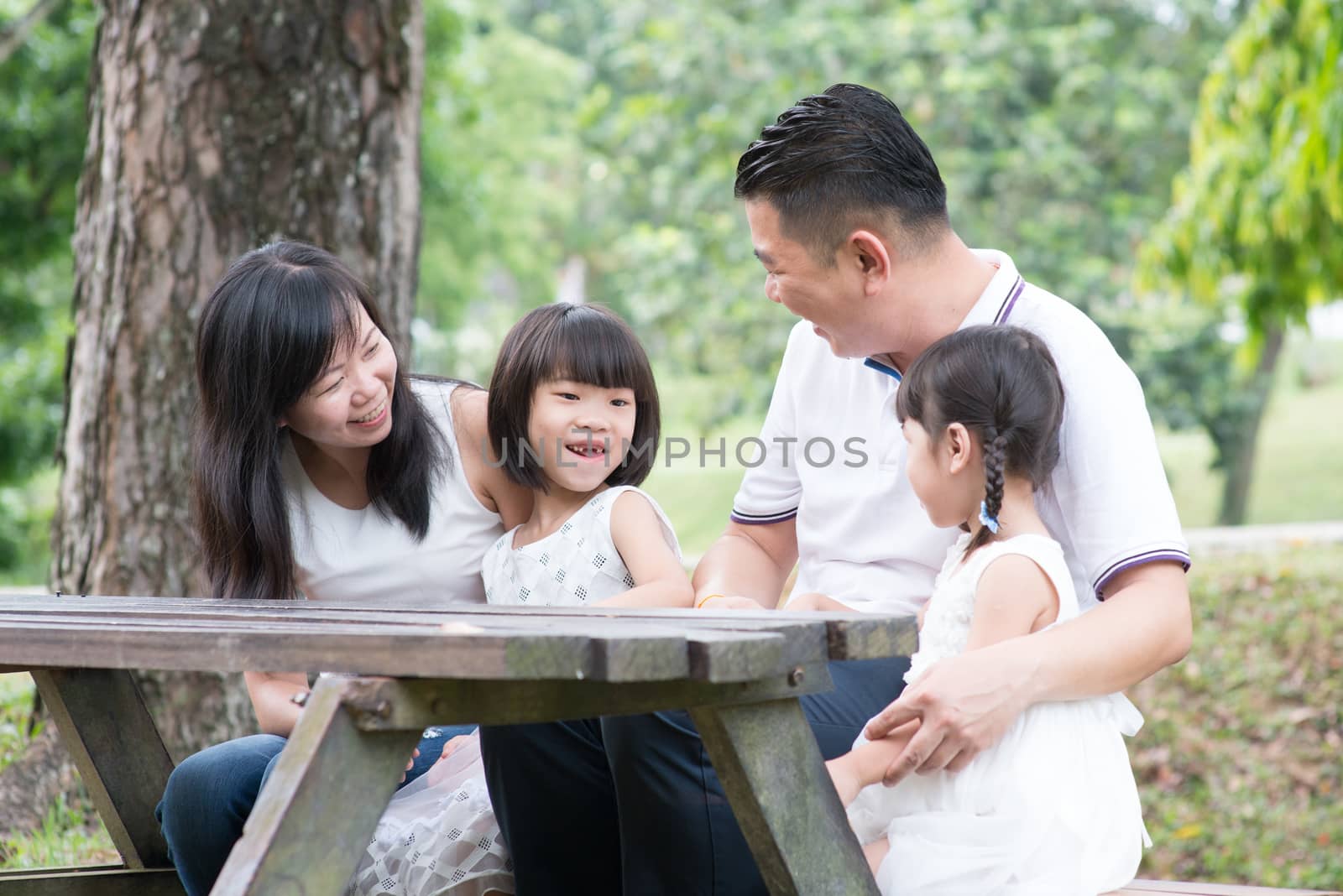 Asian family having fun at outdoor park. Empty space on wooden table.