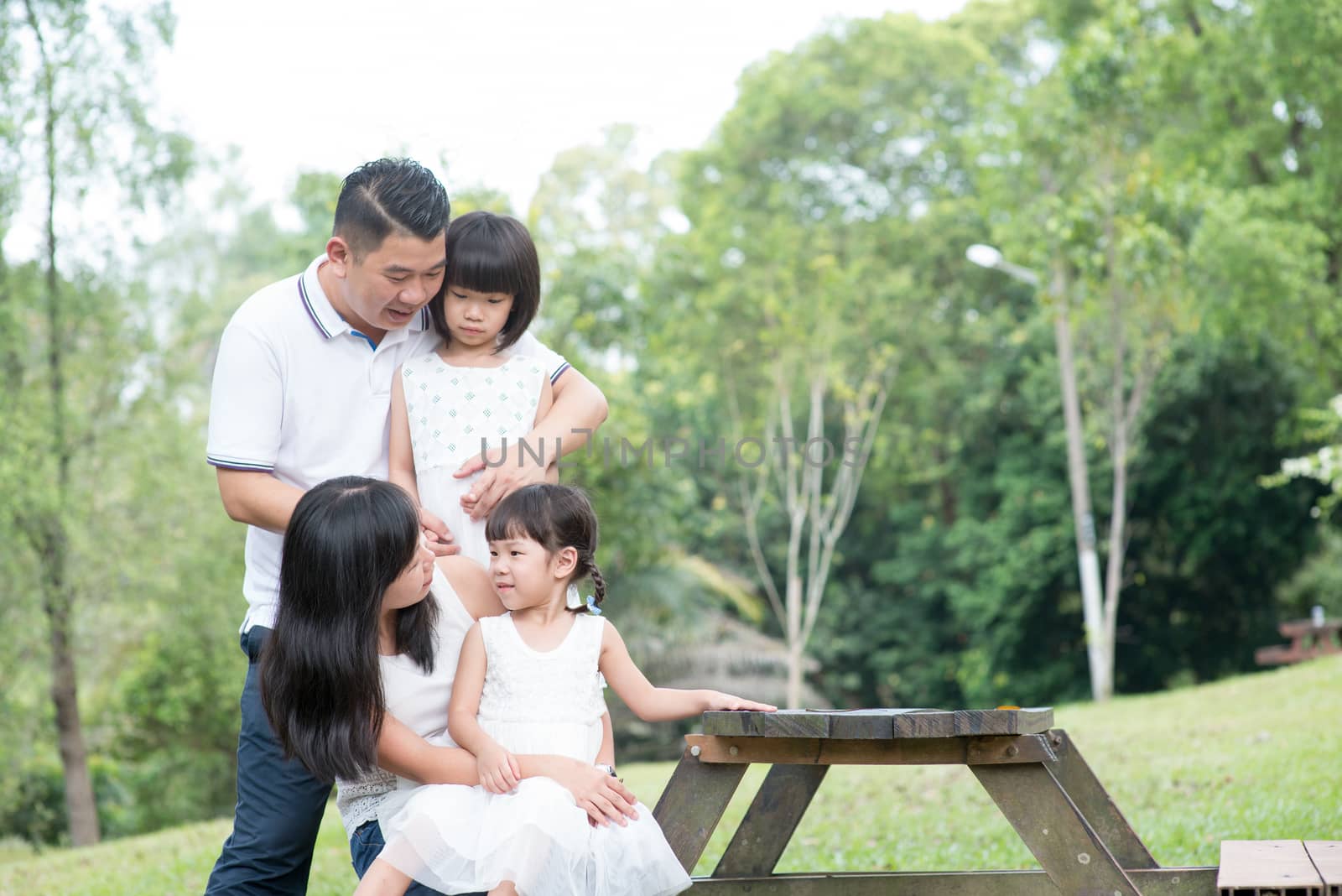 Asian family portrait. Parents and children enjoying nature at outdoor park. Empty space on wooden table.