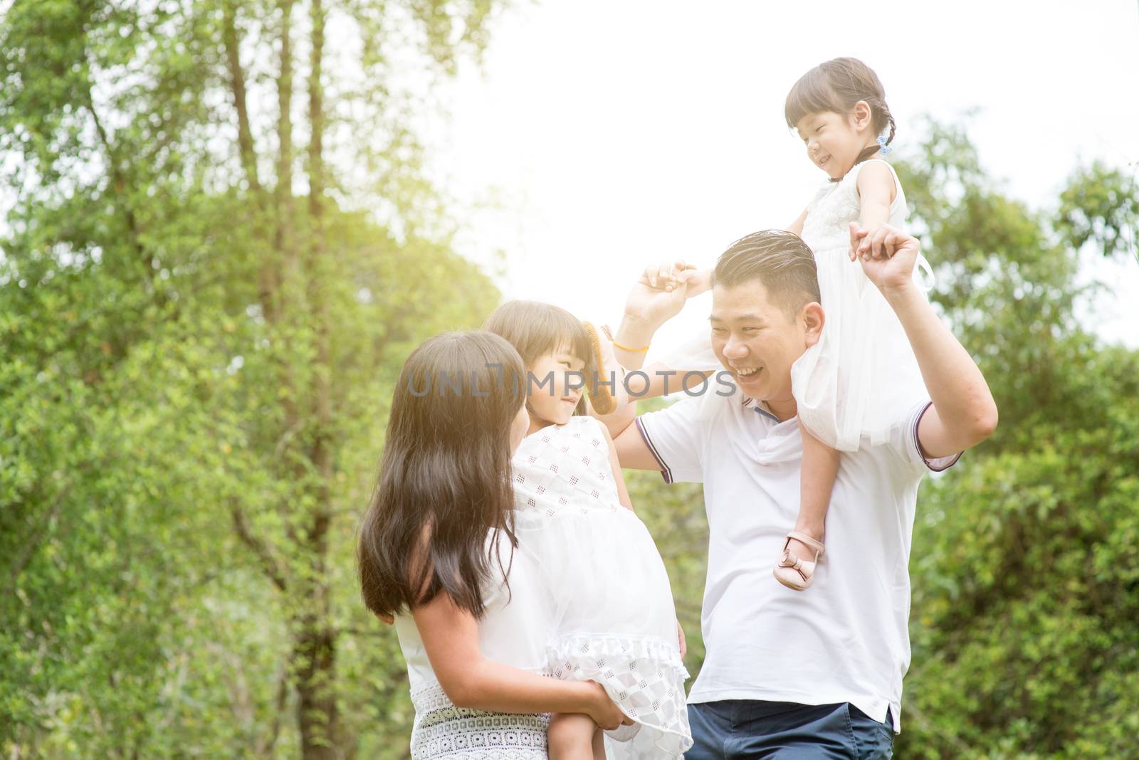 Parents and children having fun at park. Asian family outdoors portrait.