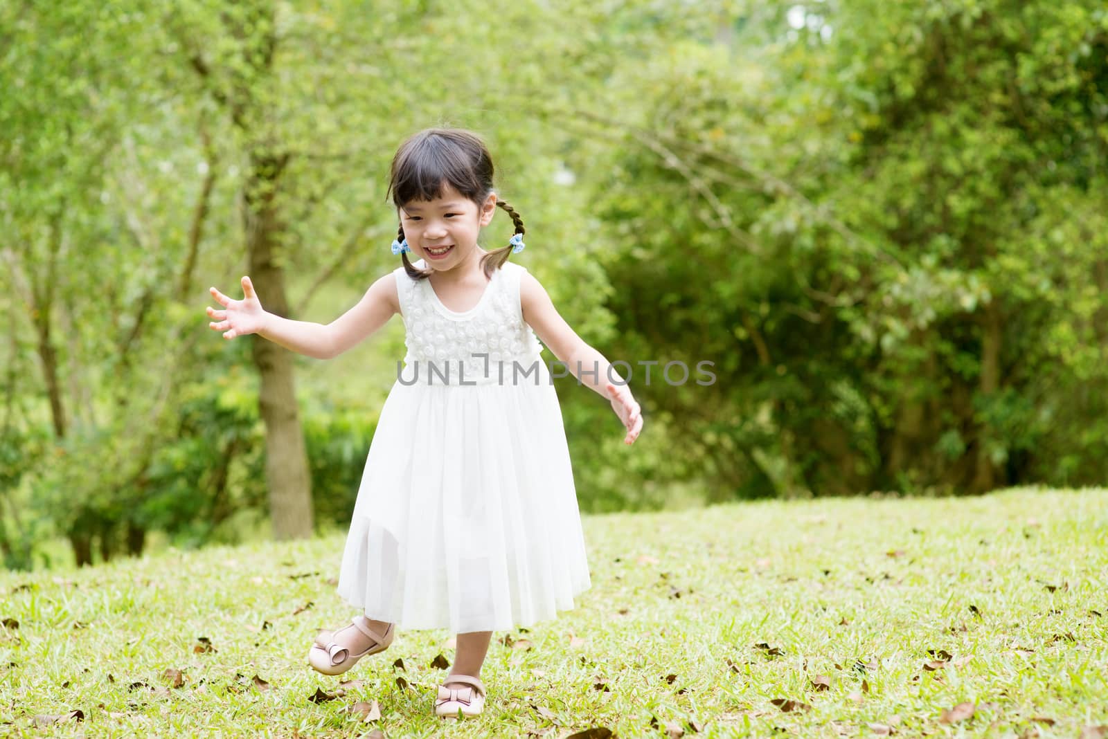 Little Asian girl running at park by szefei