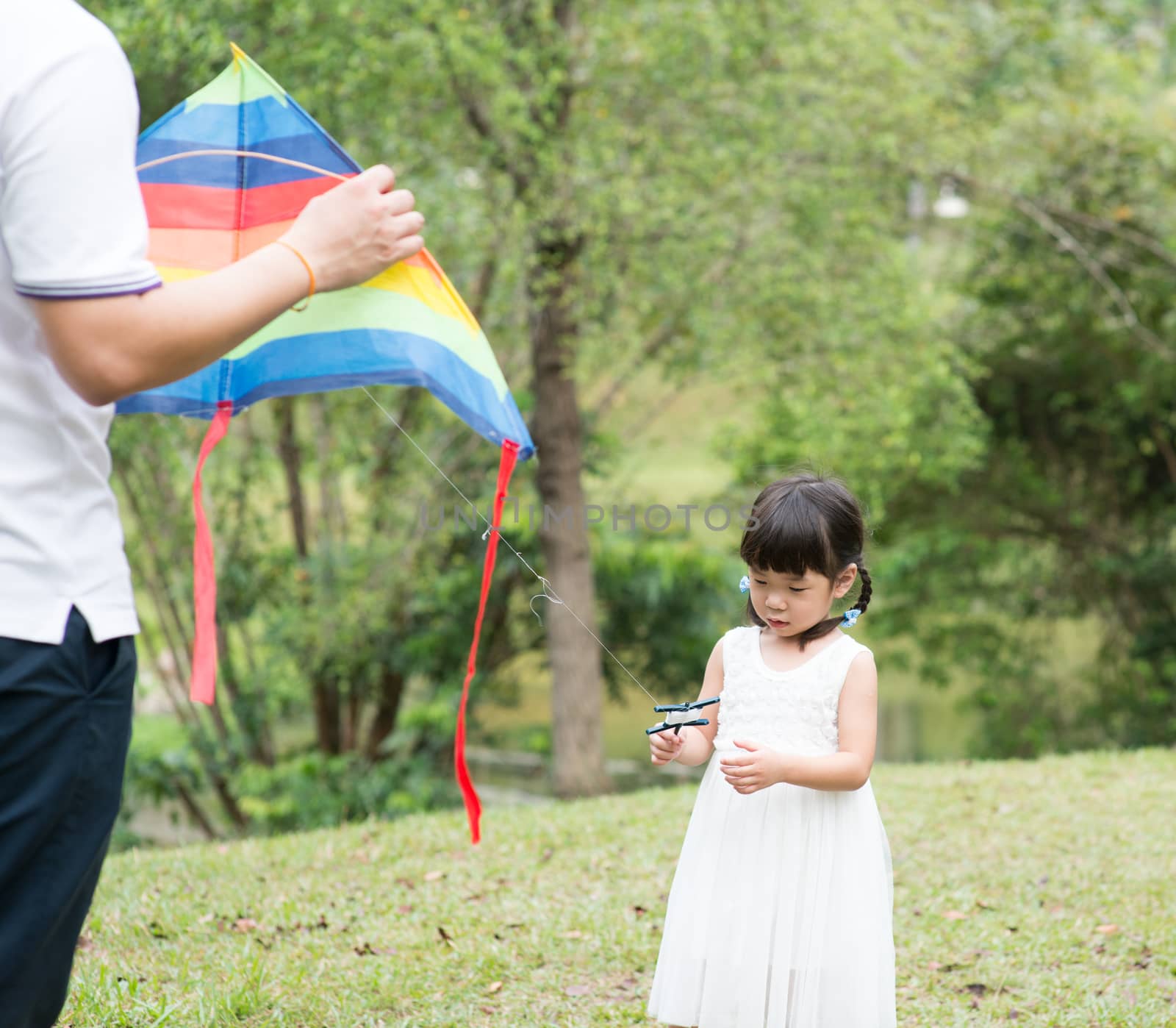 Asian family flying kite at park. by szefei