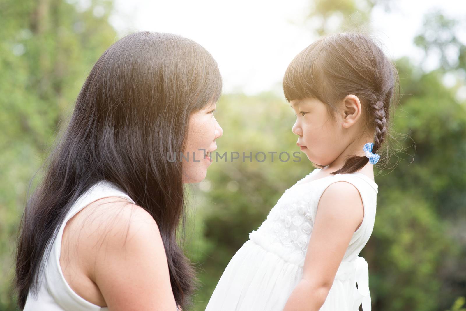 Asian family outdoors portrait. Mother and daughter having quality time at green park. 