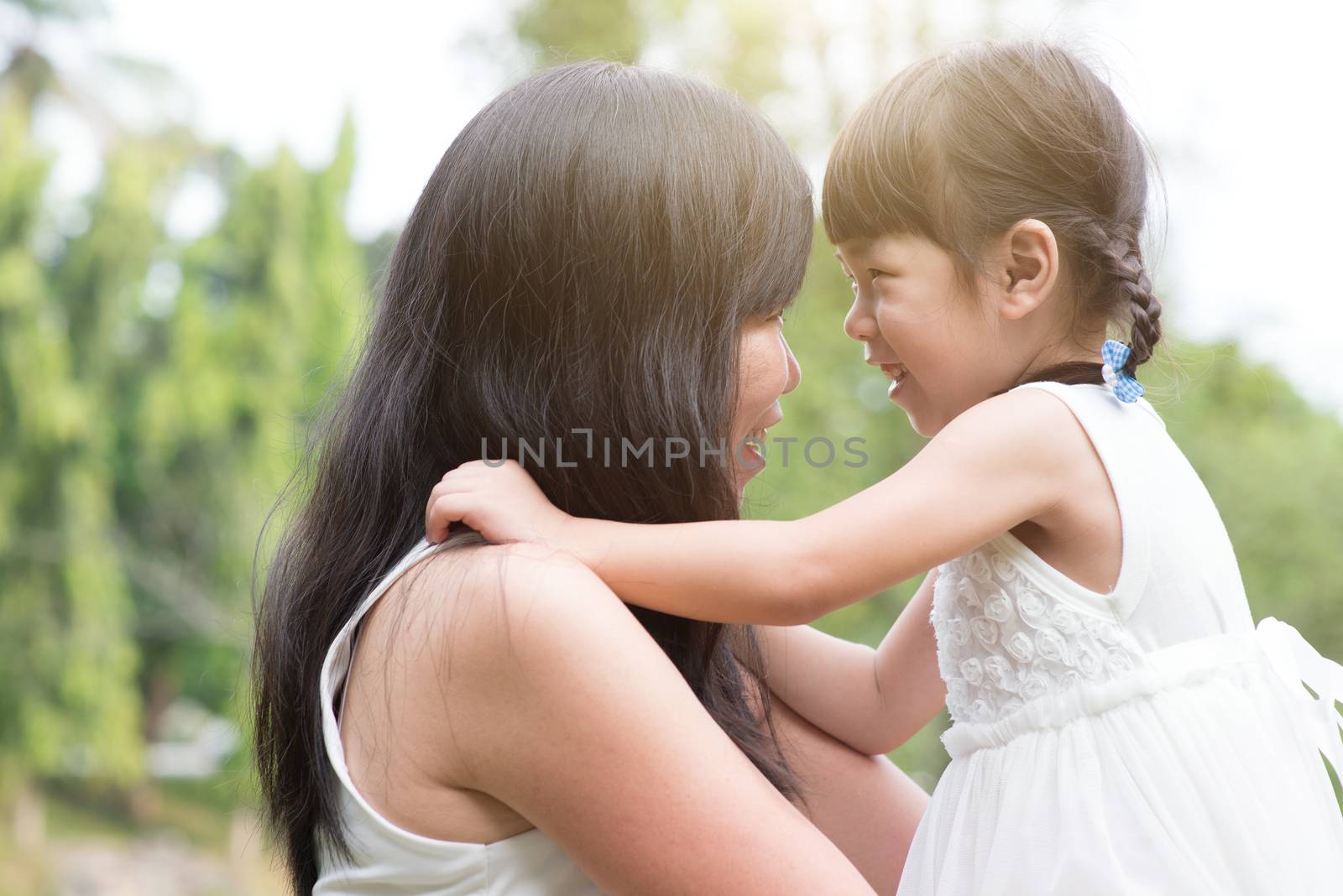 Asian family outdoors portrait. Mother and daughter enjoying moment at garden park. 