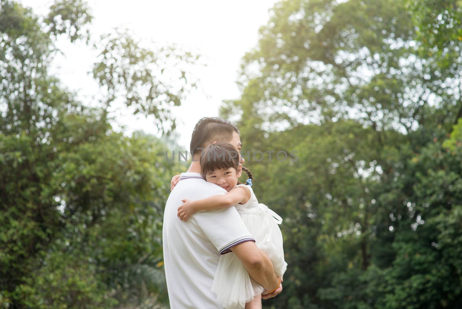 Asian family outdoors portrait. Father and daughter at green park. 