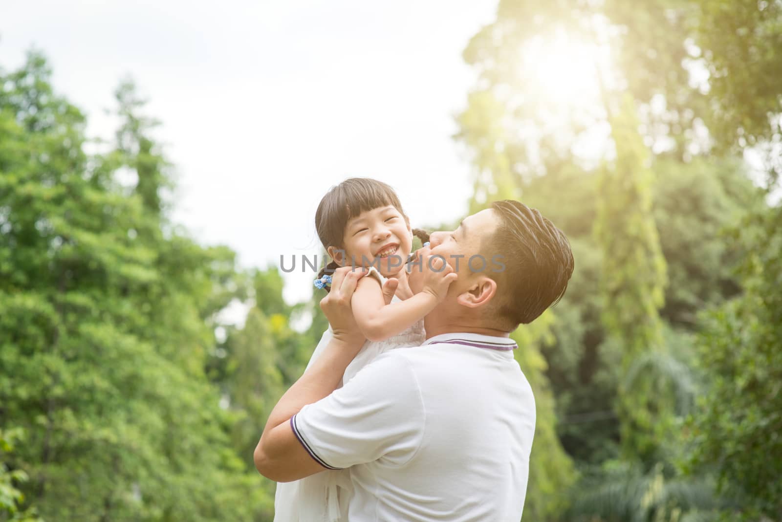 Asian family outdoors portrait. Father and daughter having fun at garden park. 