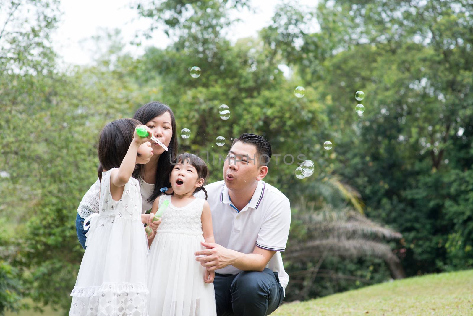 Family blowing soap bubbles outdoors by szefei