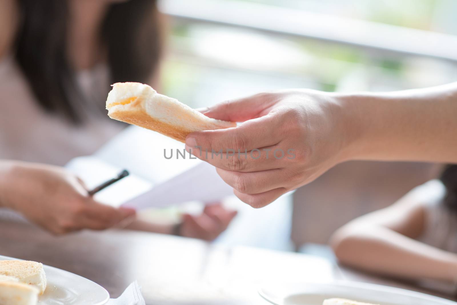 Close up human hand holding toast bread at cafeteria.