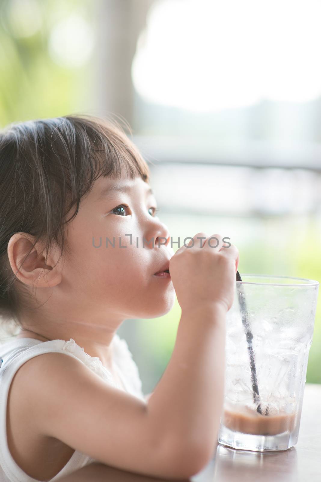 Little Asian girl drinking at cafe by szefei