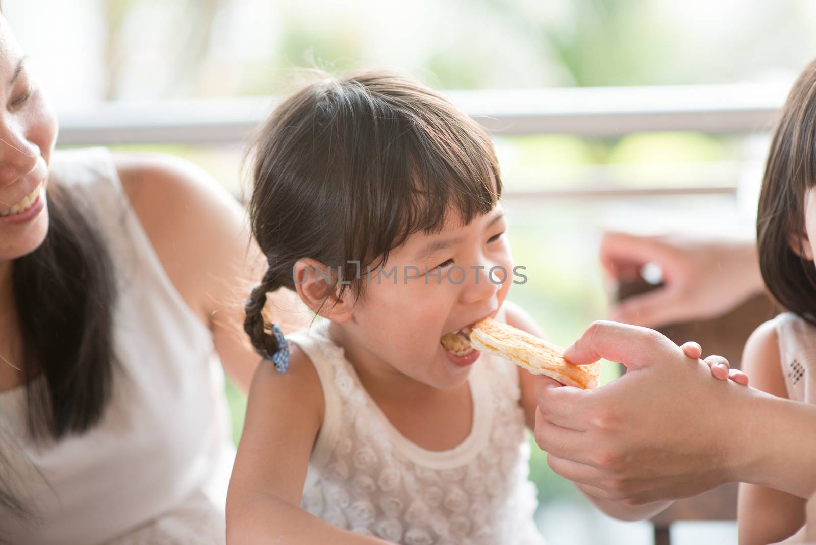 Daddy feed bread to child at cafe. Asian family outdoor lifestyle with natural light.