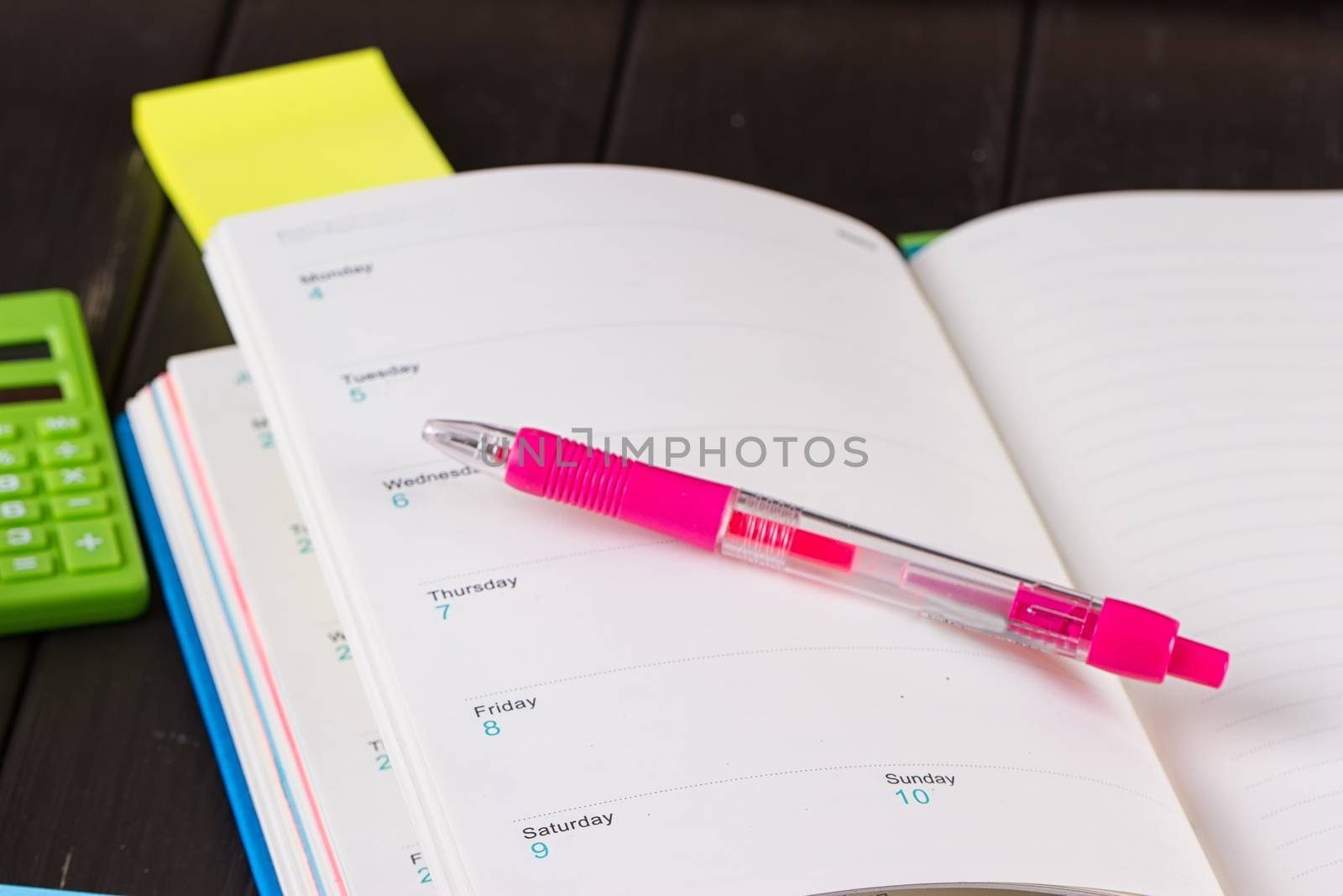 Open diary, pen on a black wooden background