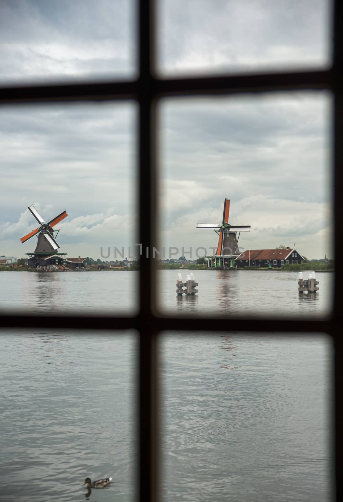 view from inside a mill to the authentic Zaandam mills on the water channel in Zaanstad village. Zaanse Schans Windmills and famous Netherlands canals, Europe.