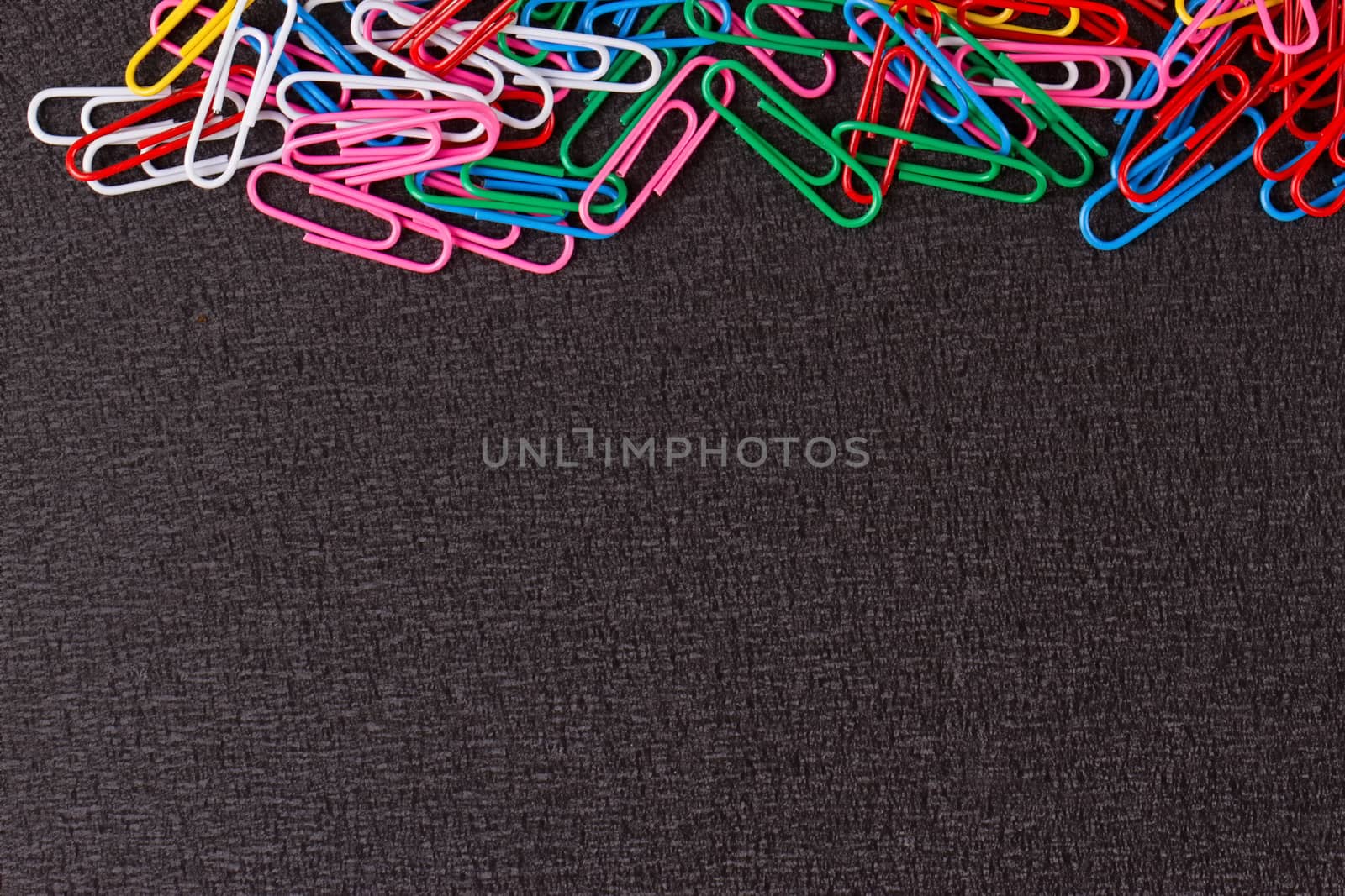 Colored paper clips on the black background