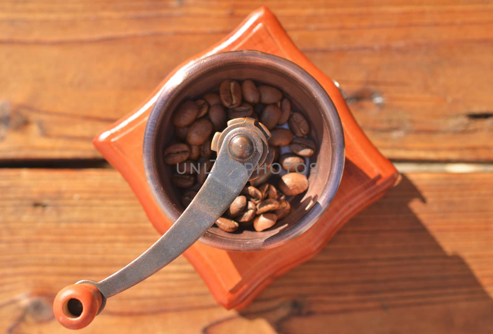 Manual coffee grinder with coffee beans on wooden planks close-up, in the center of the frame