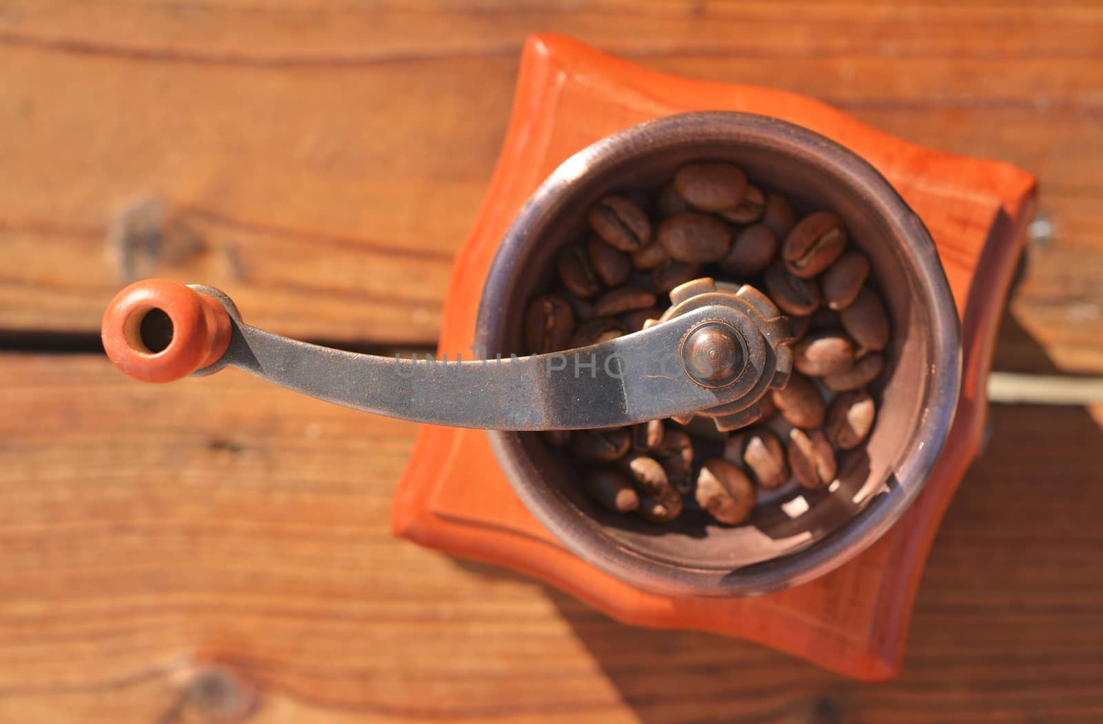 Handmade coffee grinder with coffee beans on wooden planks close-up, side-by-side in a frame