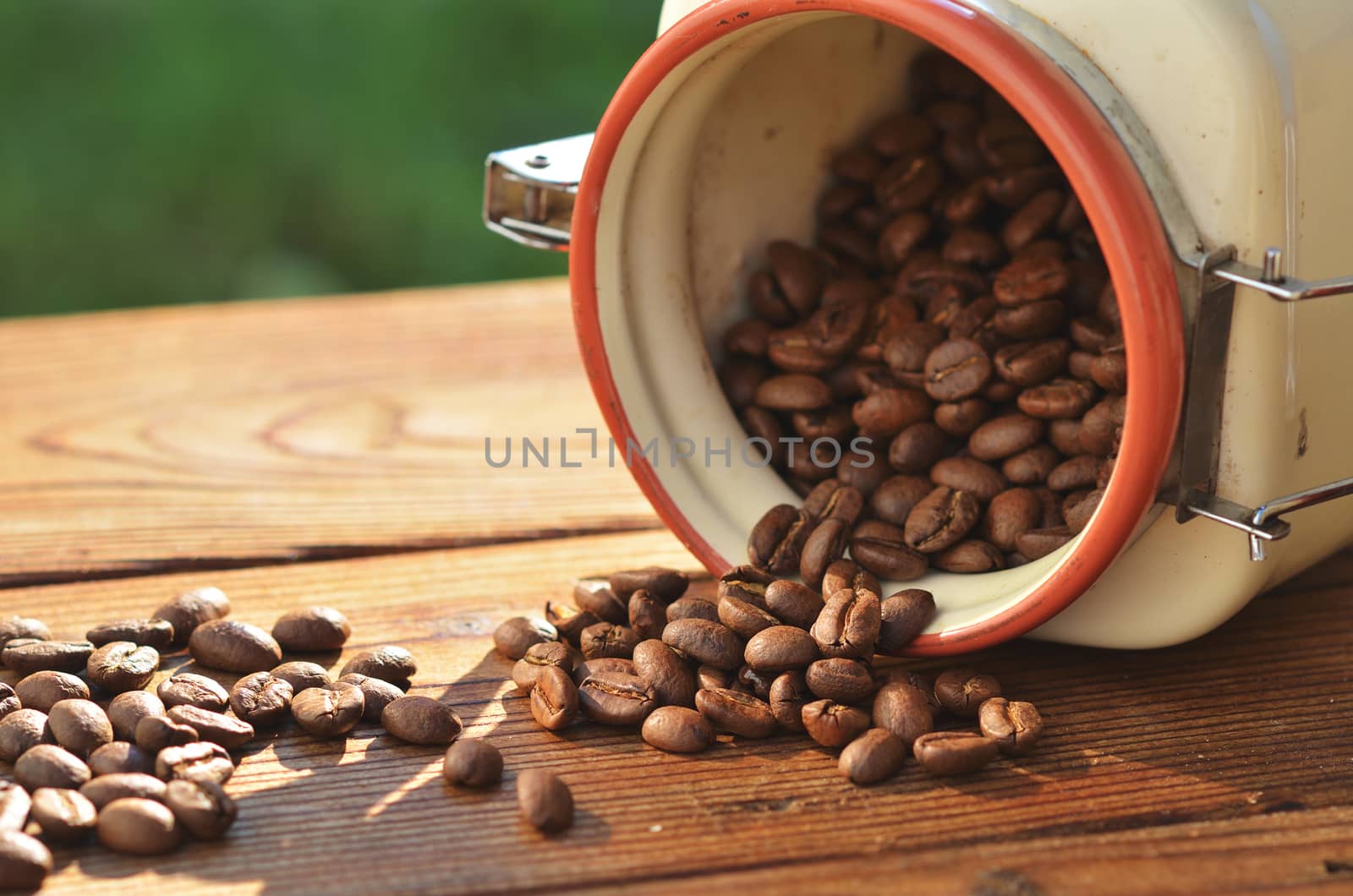 Fried coffee beans are poured from a beautiful pot of clay on a wooden board