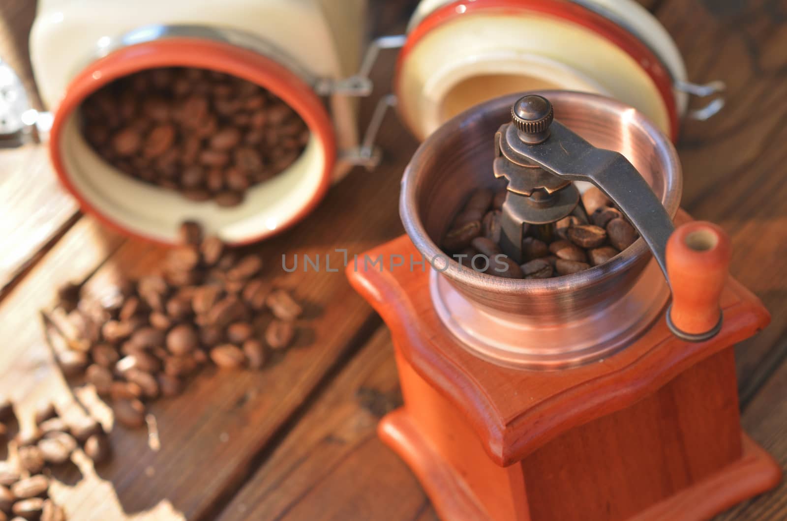 Clay pot with coffee beans and a manual coffee grinder on wooden boards, close-up